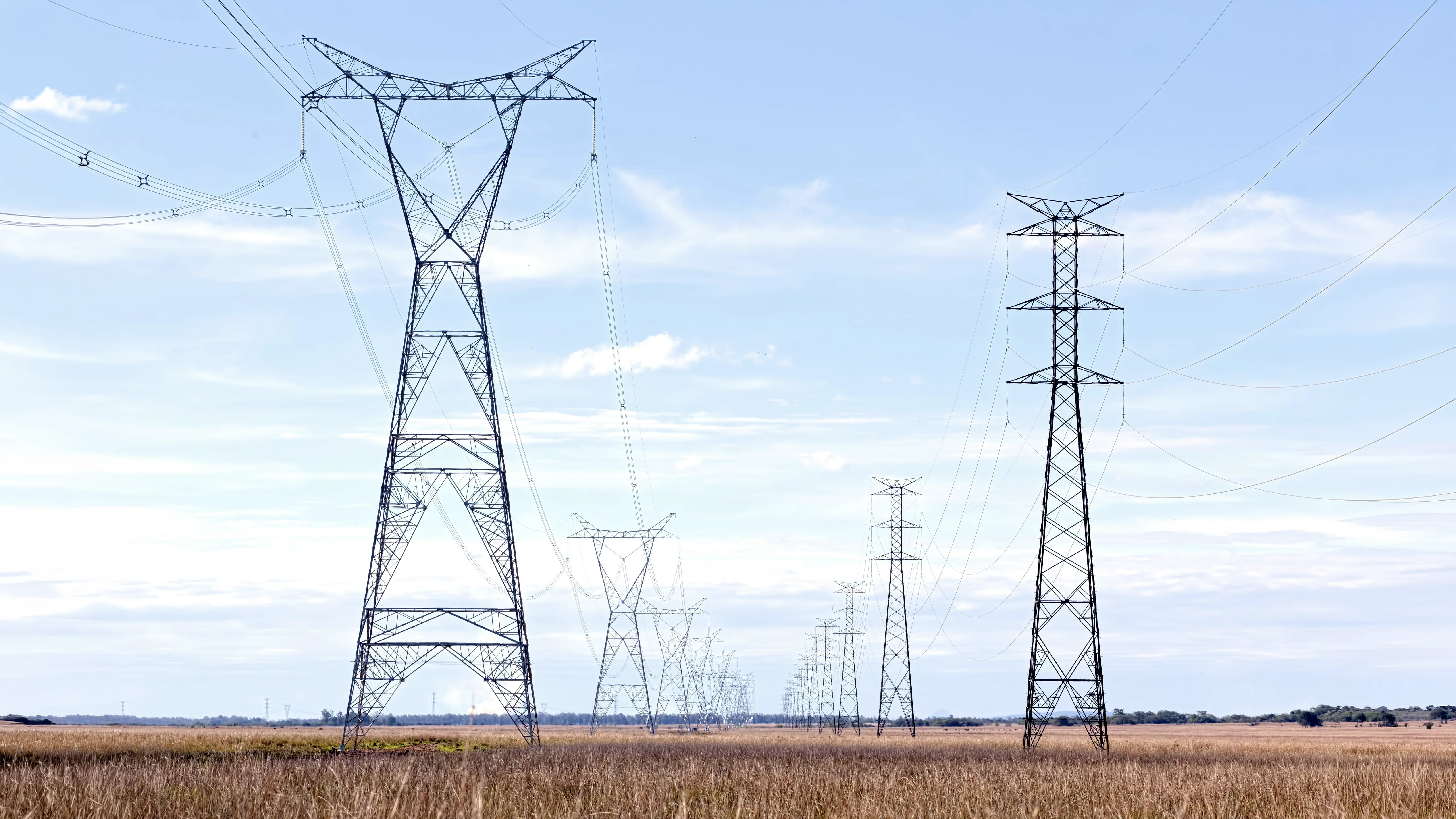 High-voltage transmission towers crossing open agricultural grassland
