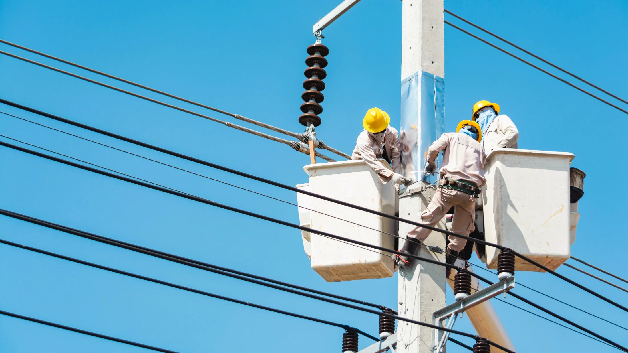 Field workers maintain electrical infrastructure — distributed energy systems require proximity to the operating condition.