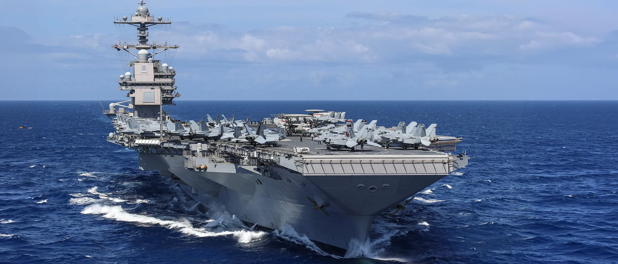 USS Gerald Ford aircraft carrier — representing the history of systems designed to process material streams at scale.